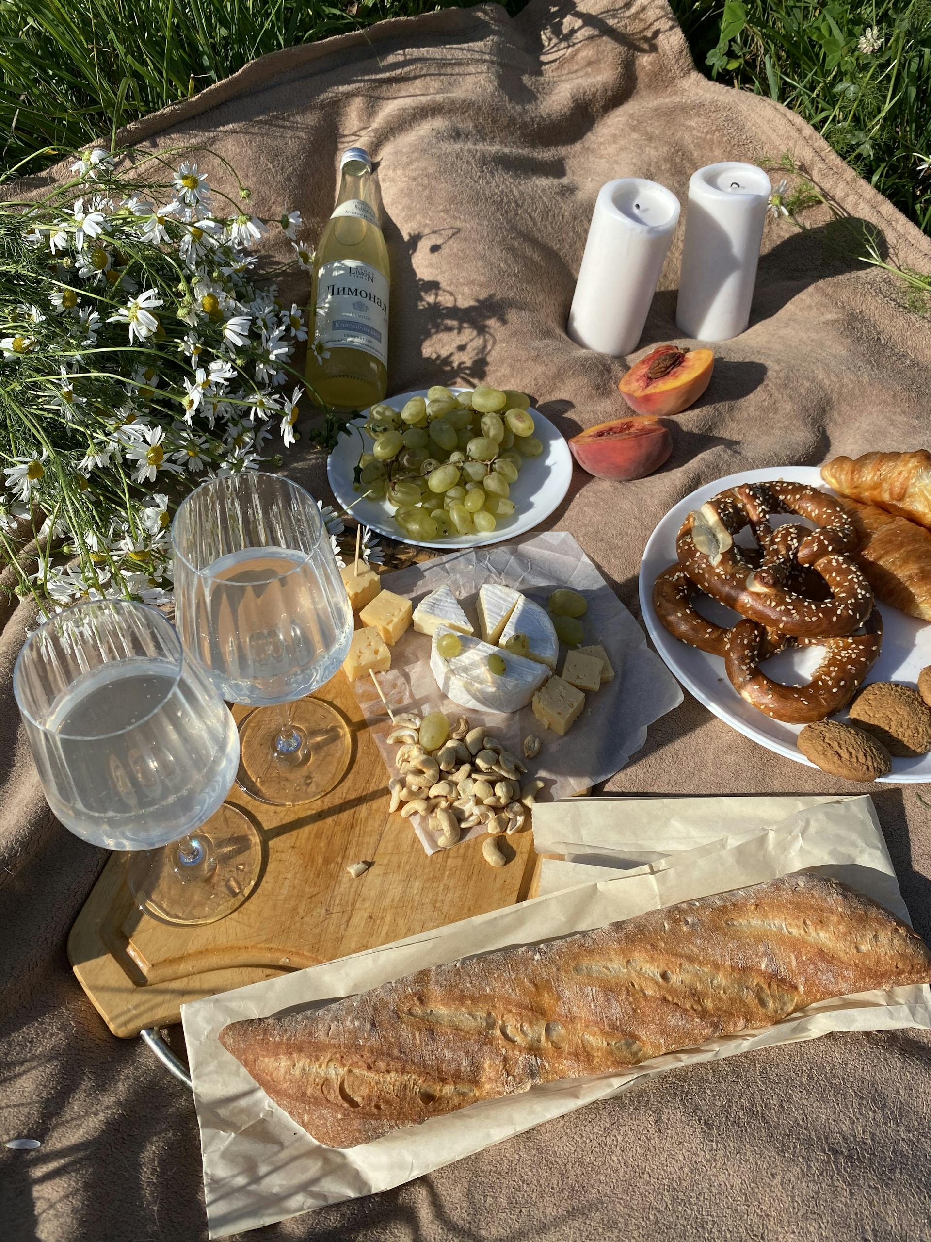 Charming picnic setup with wine, cheese, and fresh bread on a sunny day.